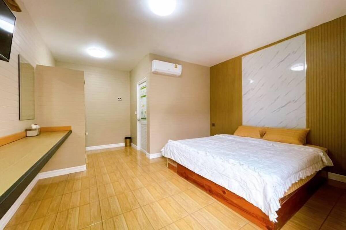 A bedroom with a bed, a bedside table, a mirror, and an air conditioning unit.