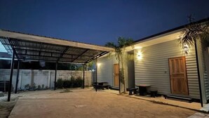 A covered outdoor area with a dirt ground, two wooden benches, and a metal structure. - IUnn Resort (Rayong)