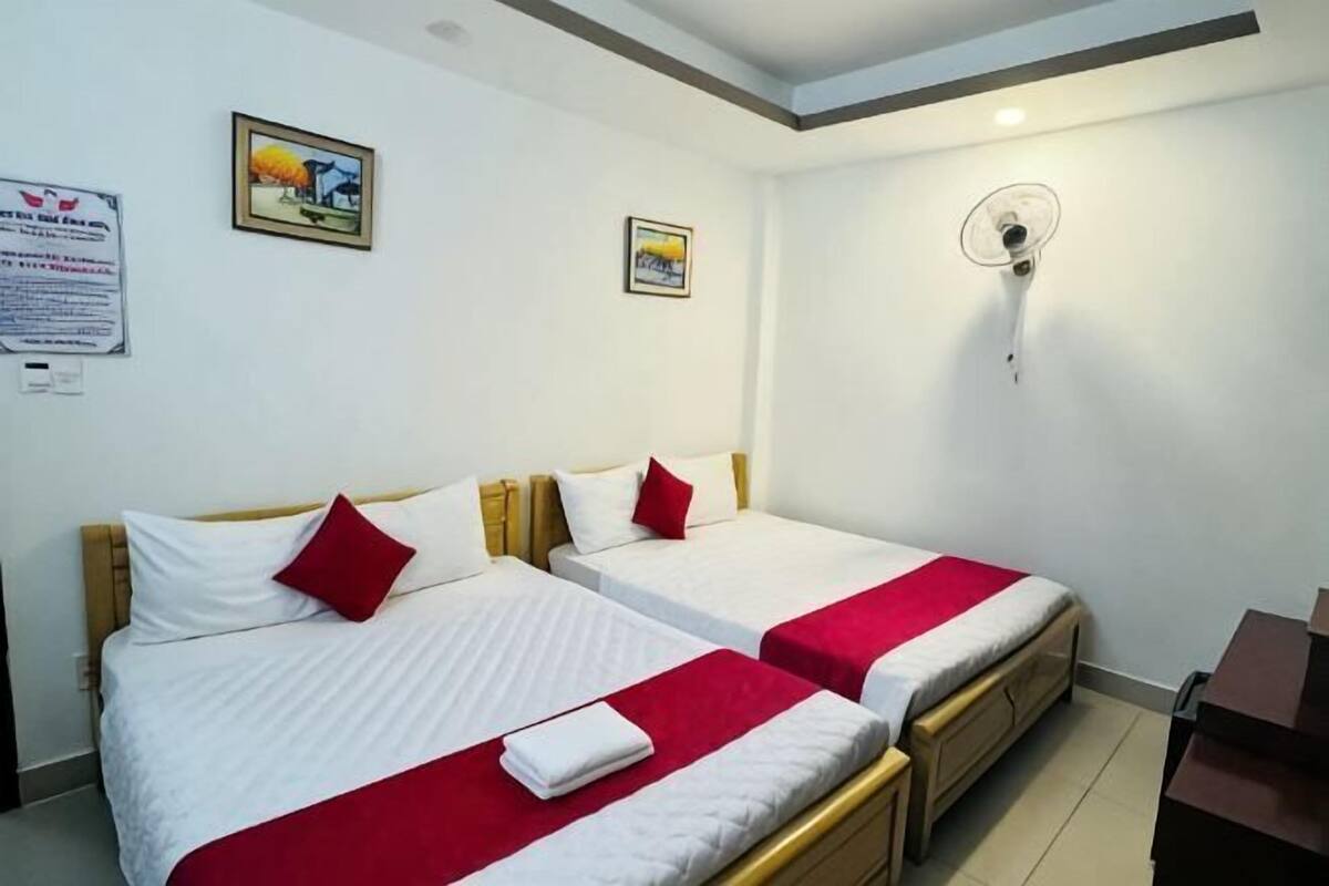 A hotel room with two beds, a ceiling fan, and a small desk.