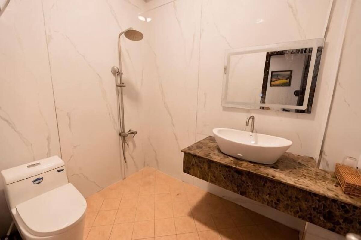 A bathroom with a toilet, sink, shower, and marble walls.