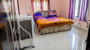A bedroom with a bed, an air conditioner, a ceiling fan, and a window with curtains. - Hare Krishna Hotel & Restaurant (Phulera)