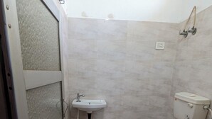 A small, basic bathroom with a toilet, sink, and shower. - Hare Krishna Hotel & Restaurant (Phulera)