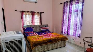 Un dormitorio con cama, ventilador de techo, aire acondicionado y ventana con cortinas.