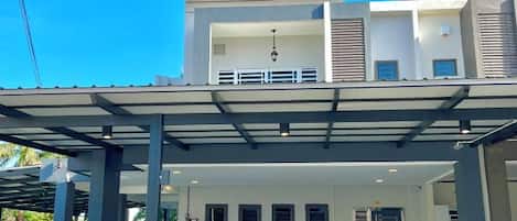 Una casa moderna de dos pisos con un porche cubierto, ventanas amplias y un balcón.