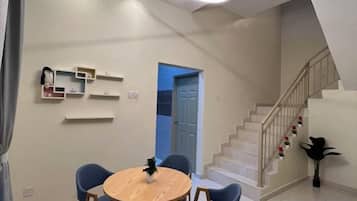 A modern interior with a dining area, a staircase, and a door leading to another room.