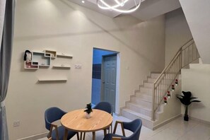 Um interior moderno com uma área de refeições, uma escada e uma porta que dá para outro quarto.