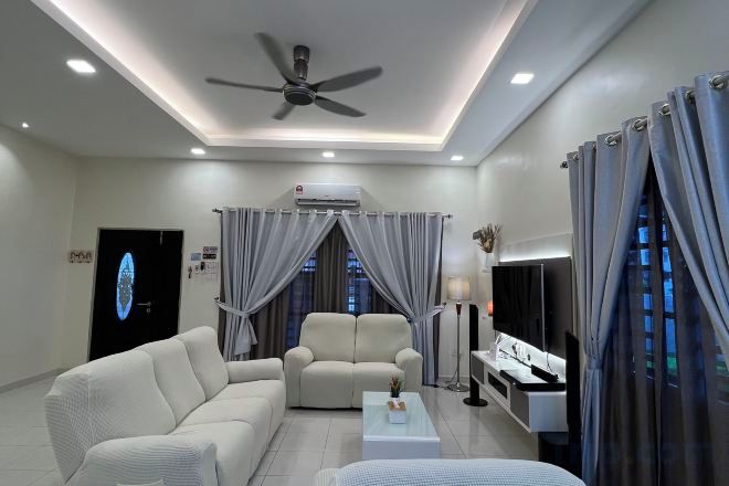 A modern living room with a sofa, armchair, coffee table, and a flat-screen TV.