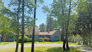 Ein Haus mit Vorgarten, einem Schotterweg und einem großen Baum im Vordergrund.