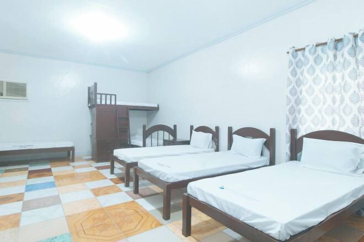 A room with three wooden beds, a bench, and a small table.