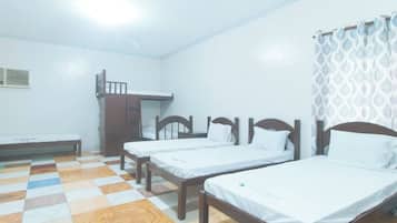 A room with three wooden beds, a bench, and a small table.