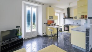 A modern kitchen with a dining area, a TV, and a balcony. - Lovely Apartment Overlooking the Lake (Carate Urio)