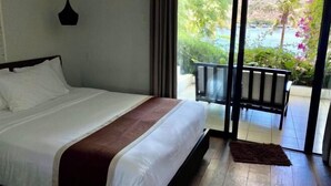 Une chambre d’hôtel avec un lit, une vue sur un balcon agrémenté de plantes et un plan d’eau.