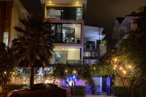 A multi-story building with balconies, a car parked in front, and decorative lights. - M Villa Nha Trang (Nha Trang)
