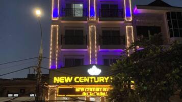 A hotel with illuminated signage, multiple floors, and a balcony.