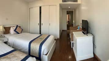 Habitación de hotel con dos camas, un escritorio, televisor y armario.