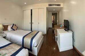 Une chambre d’hôtel avec deux lits, un bureau, une télévision et une armoire.