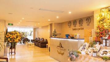 A hotel reception area with a reception desk, a clock, and a wall-mounted clock.