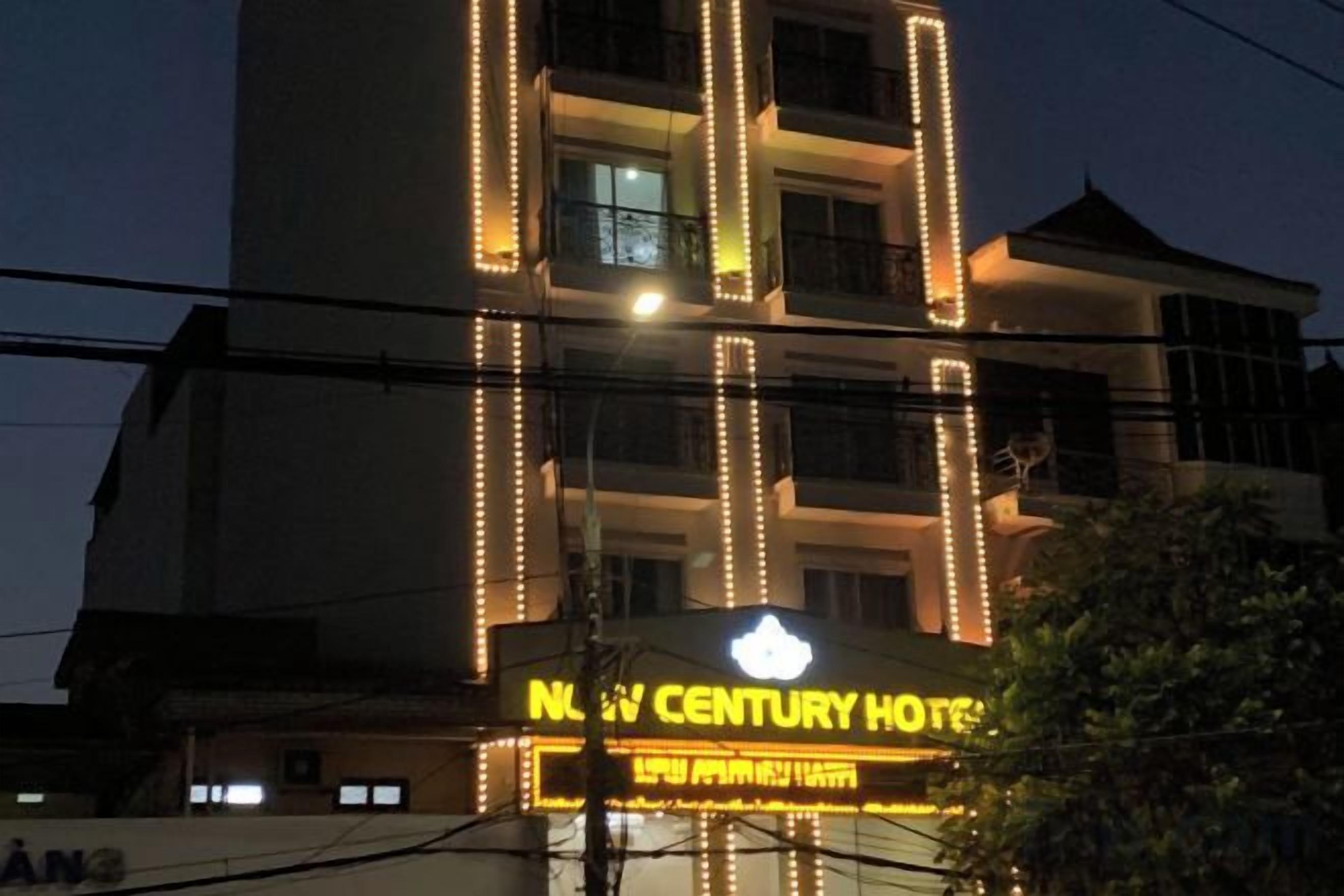Un hotel amb un cartell ben visible, diverses plantes i un balcó.