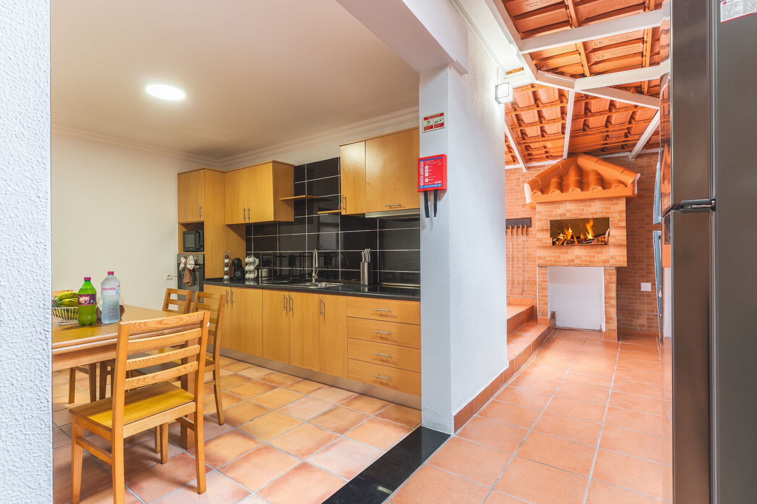 Une cuisine de taille réduite, avec des meubles en bois, un plan de travail noir et un sol carrelé.