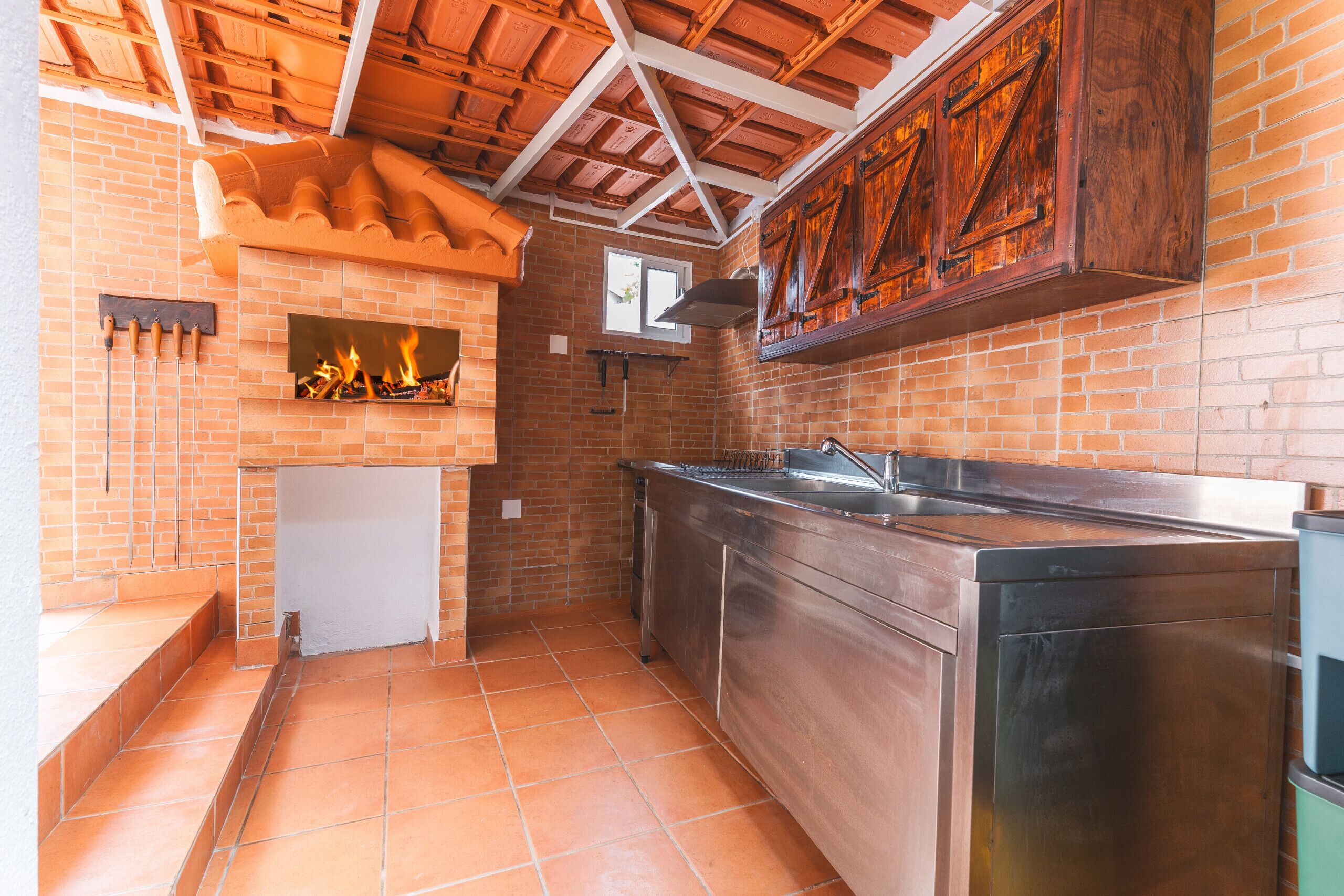 A kitchen with a brick wall, wooden ceiling, and stainless steel appliances.