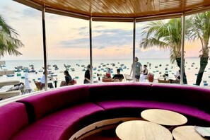 A beachside seating area with a view of the beach and boats. - Phở Homestay (Phan Thiet)