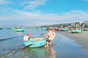 A beach with boats and people. - Phở Homestay (Phan Thiet)
