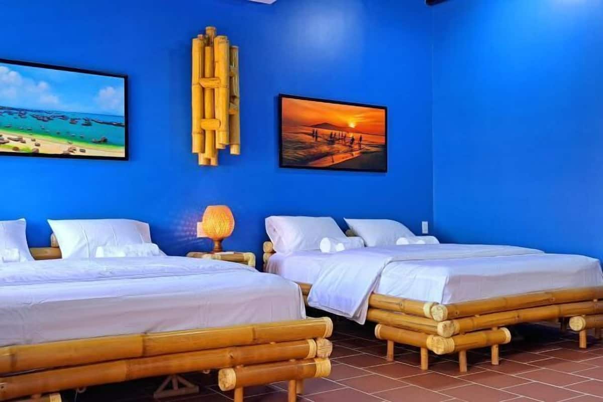 Ein Zimmer mit zwei Betten, einer blauen Wand und zwei gerahmten Bildern.