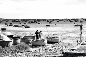 A beach with several boats and a few people standing near them. - Phở Homestay (Phan Thiet)