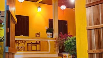 A yellow-walled room with a wooden bench, a table, and a potted plant.