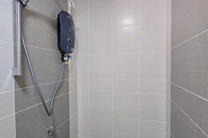 Zona de ducha con cabezal de ducha de mano y panel de control en la pared.