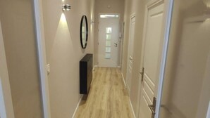 A hallway with light-colored walls, a wooden floor, and a door at the end. - Apartment Centre Carmes (Toulouse)