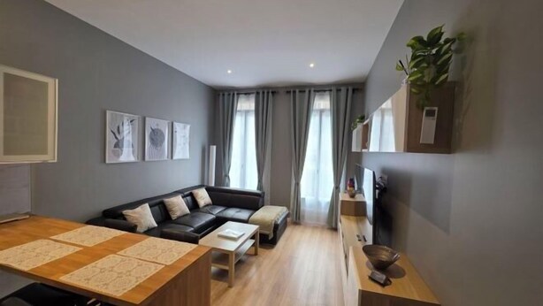 A modern living room with a sofa, coffee table, and a dining area. - Apartment Centre Carmes (Toulouse)