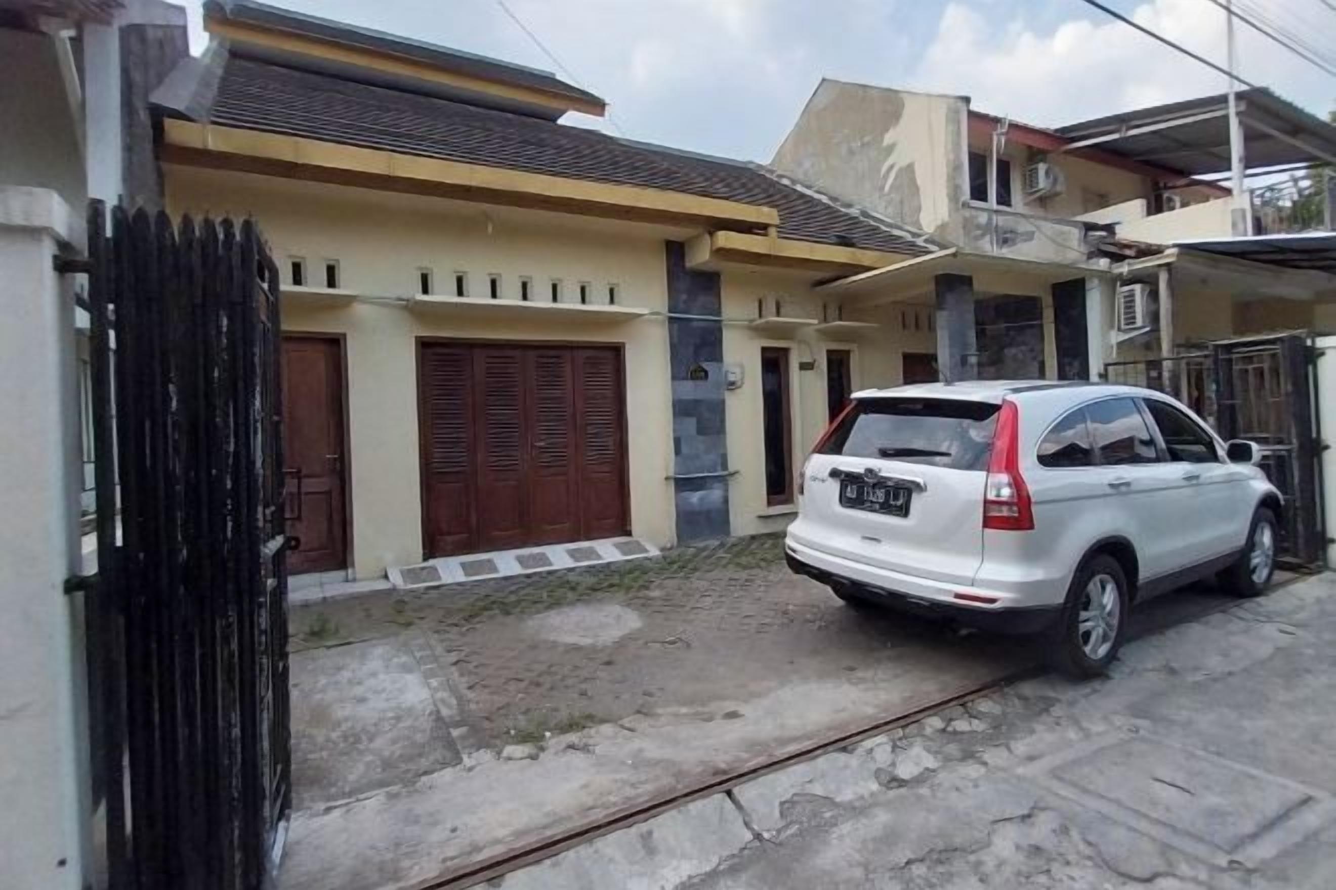 A residential building with a parked white car, a gated entrance, and a visible garage door.