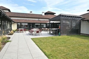 An outdoor patio area with tables and chairs, a covered seating area, and a grassy lawn. - Holiday Inn BIRMINGHAM - BROMSGROVE by IHG (Bromsgrove)