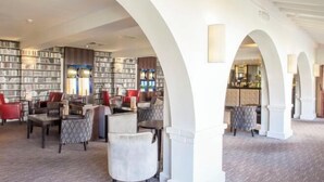Una biblioteca amplia con estanterías, asientos cómodos y una zona de bar.