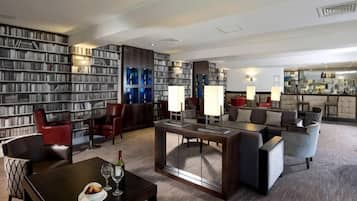 A hotel lobby with a large bookshelf, seating area, and a bar.