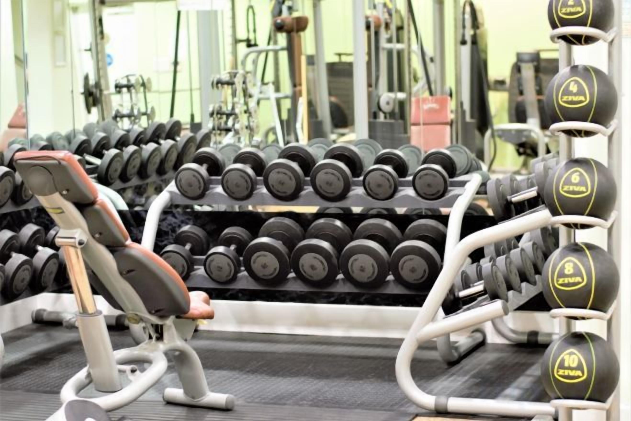 Et fitnesscenter med forskellig træningsudstyr, herunder håndvægte og styrkemaskiner.