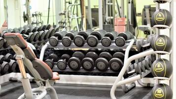 Et fitnesscenter med forskellig træningsudstyr, herunder håndvægte og styrkemaskiner.
