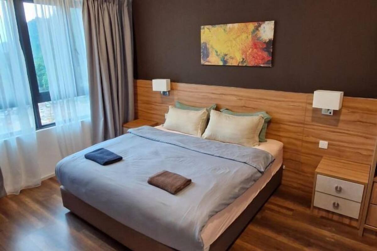 Ein Hotelzimmer mit einem großen Bett, einem Holzkopfteil, zwei Nachttischen, einer Wandlampe und einem farbenfrohen abstrakten Gemälde.