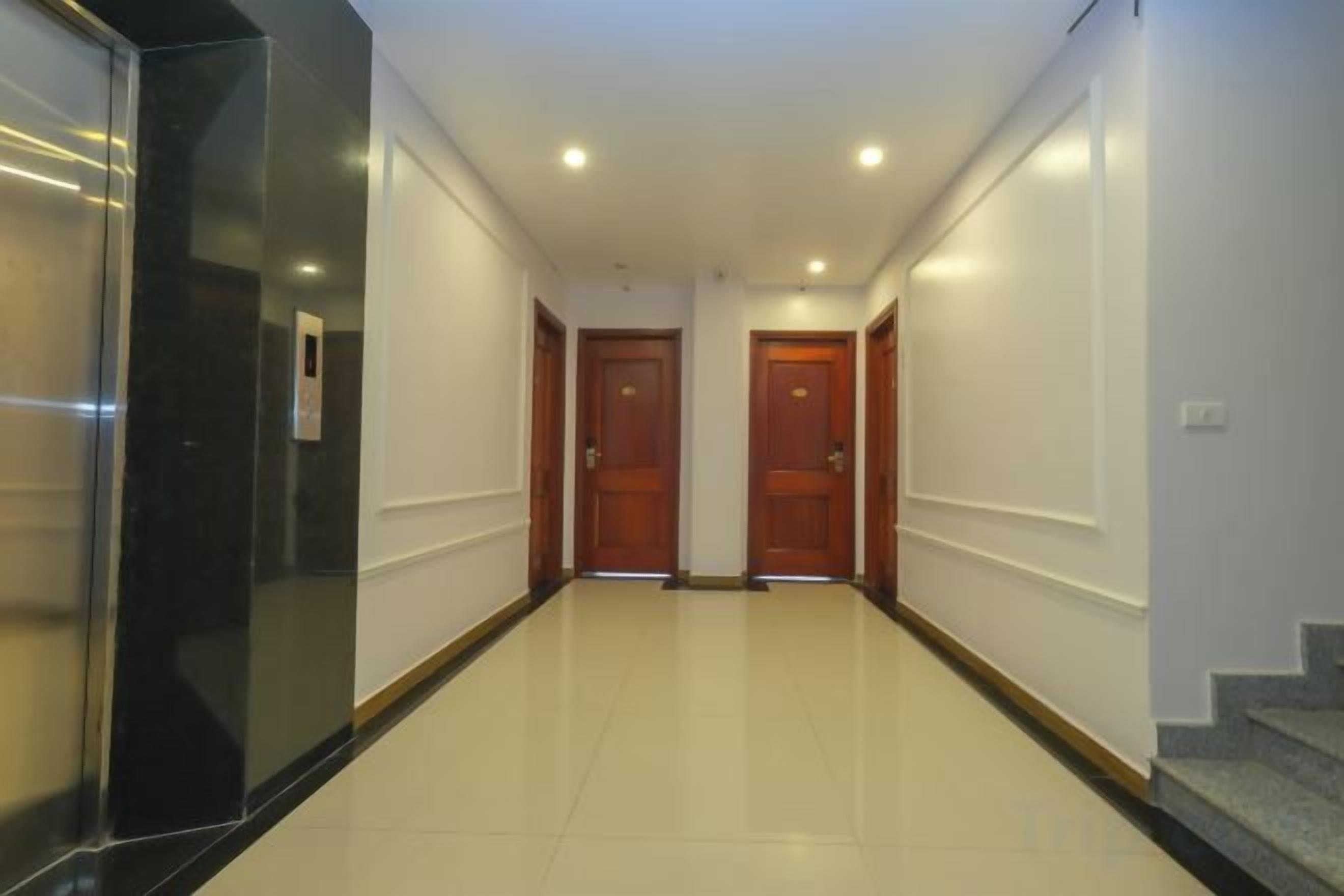 A hallway with two wooden doors, a black elevator, and a staircase on the right.