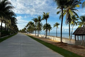 A coastal walkway lined with palm trees and a beach on one side. - Anise hotel (Phu Quoc Island)