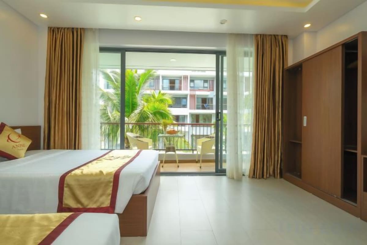 A hotel room with a balcony, a bed, a wardrobe, and a table with chairs.