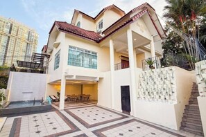Um edifício de dois andares com um alpendre coberto, uma escadaria e uma piscina.