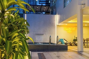 A pool area with a water feature, seating, and a neon sign. - JB Town Villa by RR JBcity (Johor Bahru)
