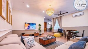 A modern living room with a sofa set, a coffee table, a TV, and a chandelier. - JB Town Villa by RR JBcity (Johor Bahru)
