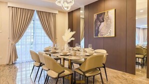 A dining area with a marble floor, beige chairs, a round table set for six, and a chandelier. - JB Town Villa by RR JBcity (Johor Bahru)