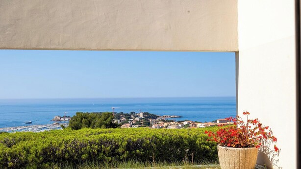 A balcony with a view of the sea, a potted plant, and a logo for 'IMM CONSULT'. - T1 apartment with 25m2 terrace and exceptional view (Bandol)