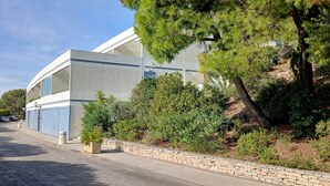 A modern building with a curved facade, a stone retaining wall, and a paved driveway. - T1 apartment with 25m2 terrace and exceptional view (Bandol)