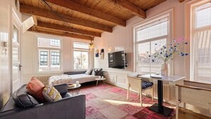 A cozy living room with a wooden ceiling, a sofa, a small table, and a TV.