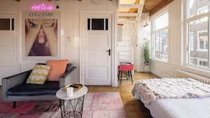 A cozy room with a sofa, a bed, a small table, and a poster on the wall.